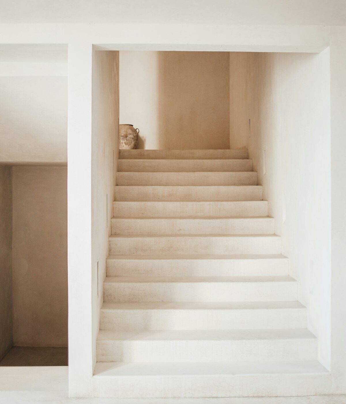 A travertine staircase rising through a calm interior