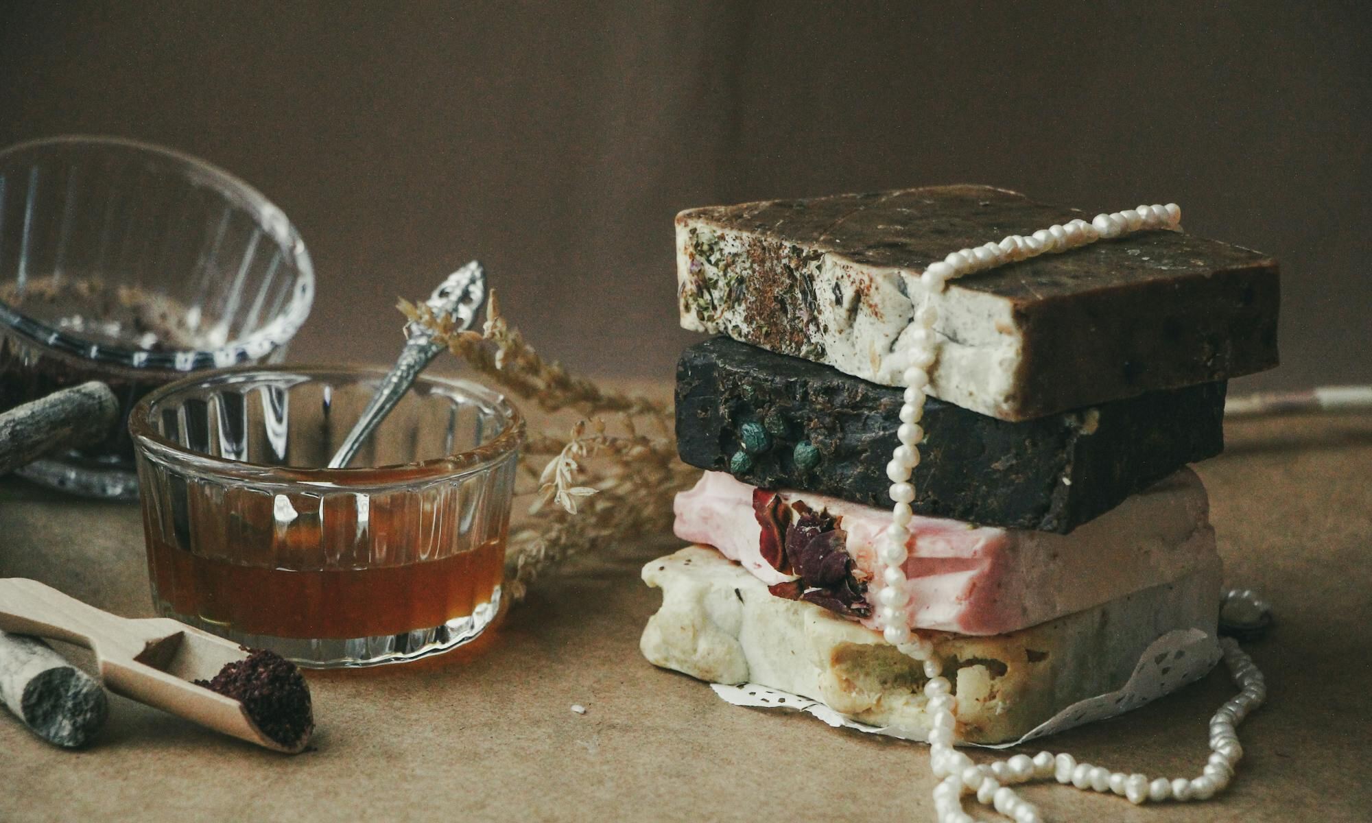 Cured cubes of Aleppo laurel soap, ochre on the outside and green within, beside laurel leaves and olives