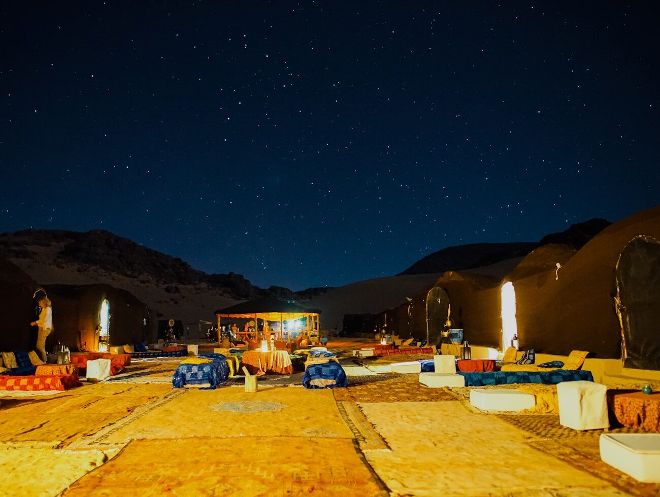 A camp lit warmly at dusk among the dunes